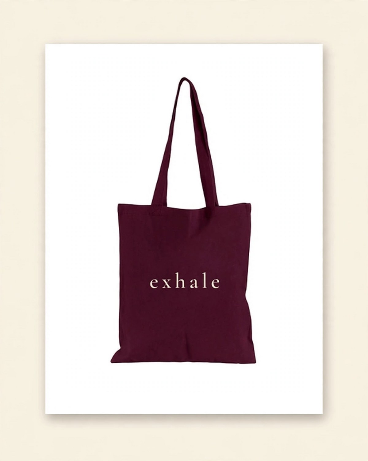 Shop mockup of the back of the Breathe Tote in burgundy canvas: the single word exhale in soft cream serif lettering, on a white card