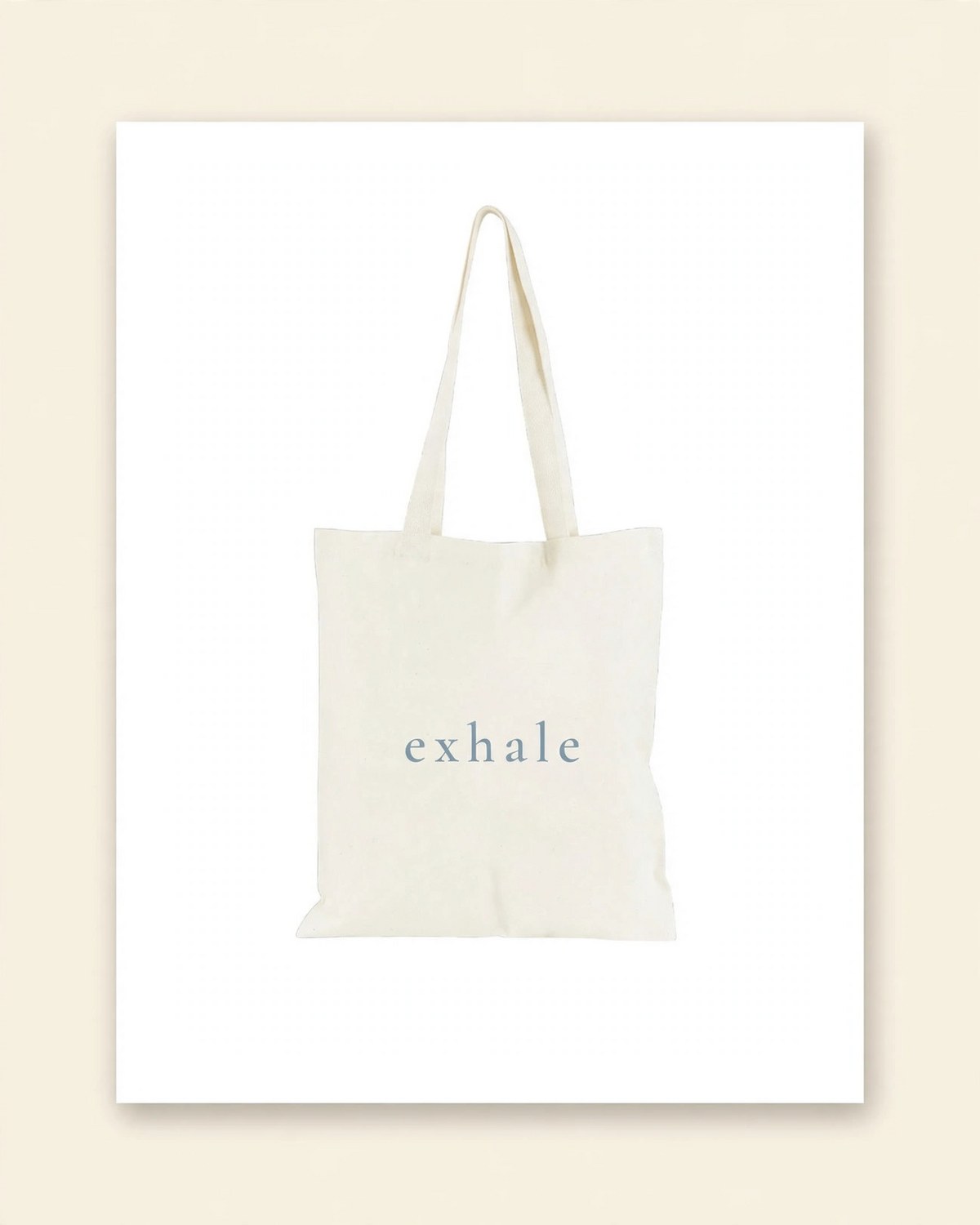 Shop mockup of the back of the Breathe Tote in natural canvas: the single word exhale in dusty-blue serif lettering, on a white card
