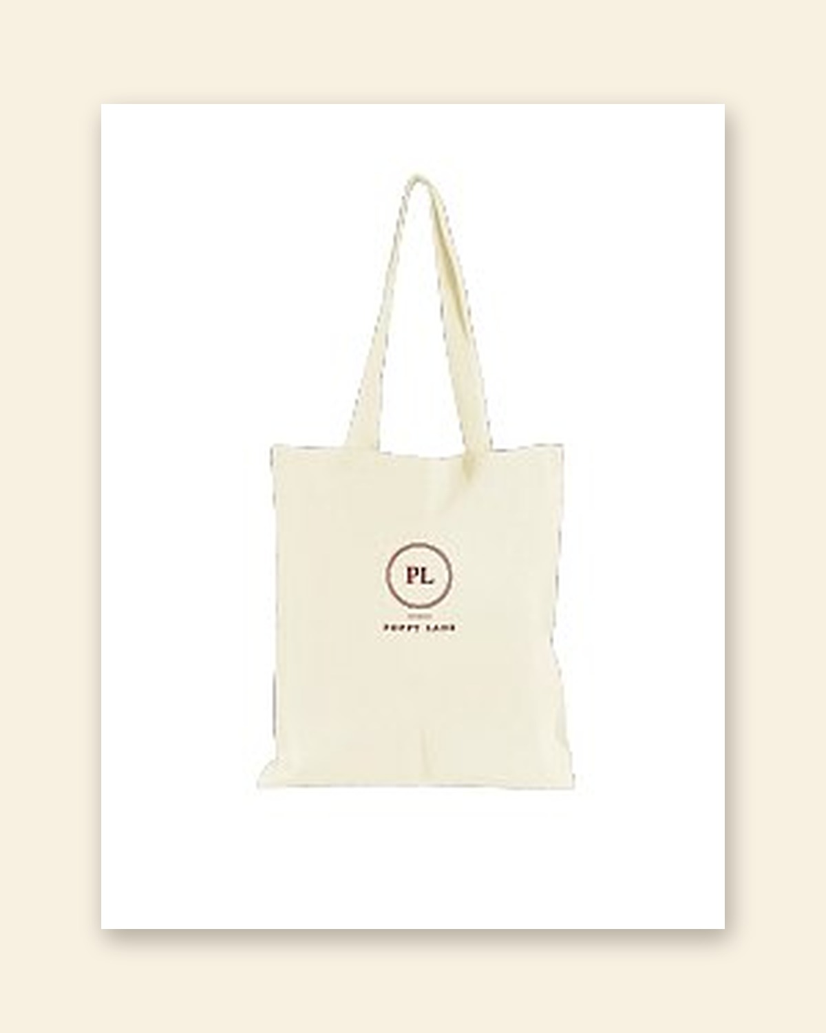 Shop mockup of the Monogram Tote in natural canvas: the PL monogram in a maroon ring with the words Poppy Lane beneath, on a white card